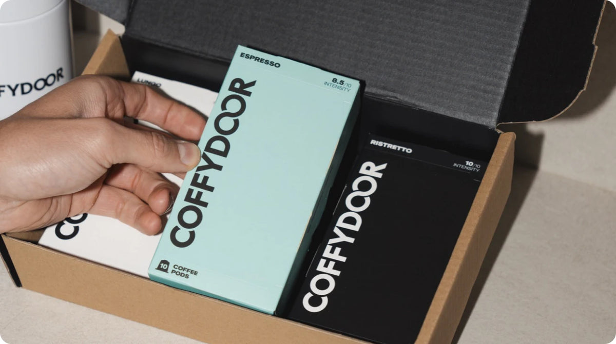 Hands lifting a Coffydoor capsule box out of a delivery box